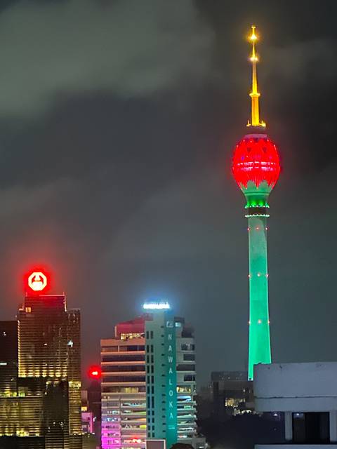Night view of Colombo Lotus Tower illuminated in red and green against a dark sky.