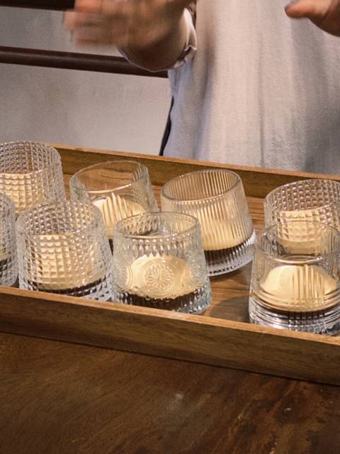 Tray of textured glass cups each holding a layer of creamy dessert waiting to be served.