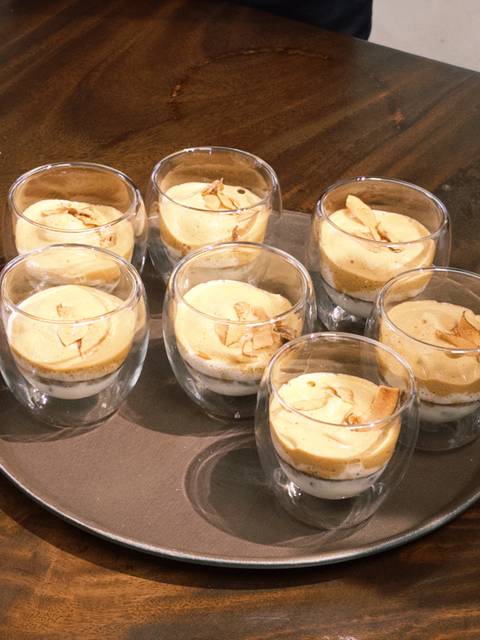 Row of rounded glasses filled with layered egg coffee topped with crunchy chips.