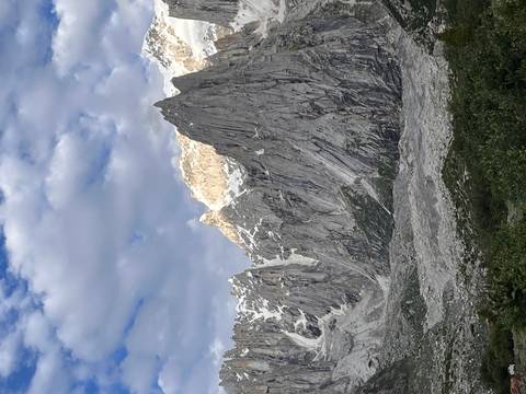 Dramatic granite spires and ridges towering above a rocky valley under partly cloudy skies.