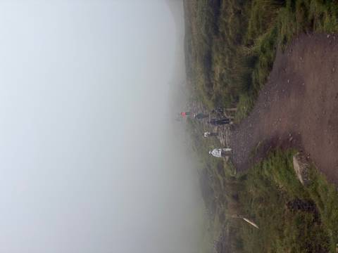 Hikers ascend a stone path that disappears into dense mountain fog.