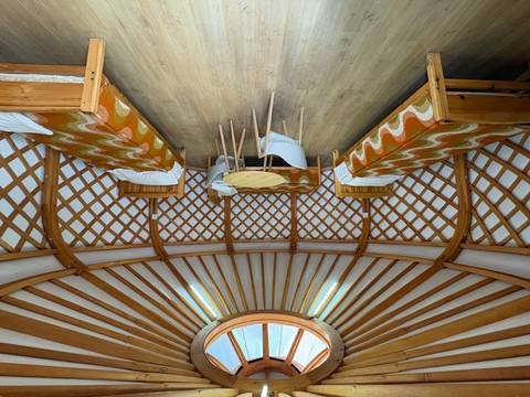 Interior of a spacious ger featuring lattice walls, twin beds and a circular skylight.
