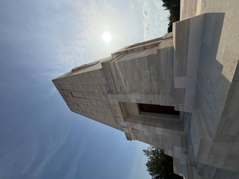 Tall limestone memorial at Gallipoli viewed from below against a hazy midday sun.
