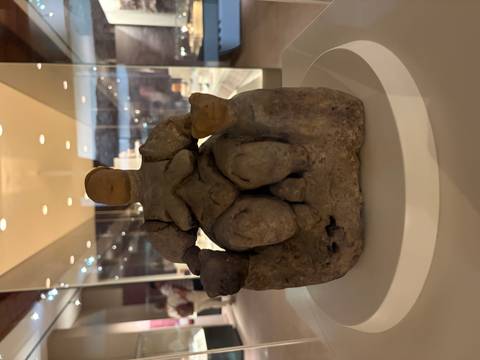 Ancient limestone figurine displayed inside a dimly lit museum case.