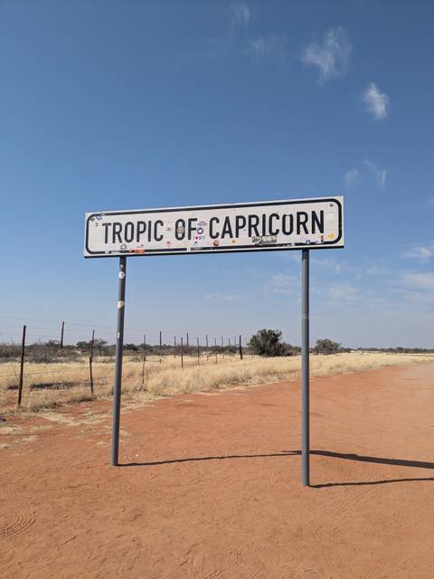 Roadside sign marking the Tropic of Capricorn in the barren Namibian landscape.