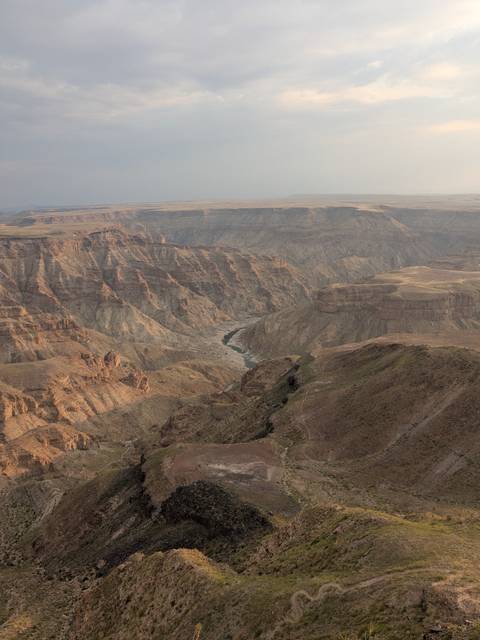 Vast panorama of Fish River Canyon with layered cliffs and a winding river far below.