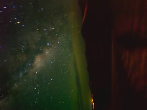 Blurry long-exposure image of a starry night sky with Milky Way over dark dunes.