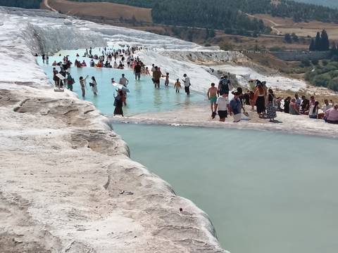 Crowds wade in the turquoise thermal pools cascading over white travertine terraces.