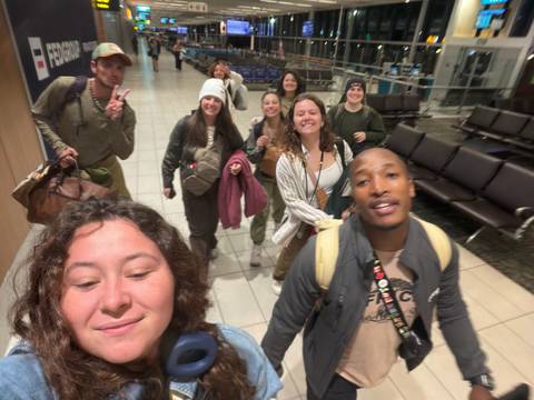 Selfie of a travel group walking through an airport terminal with luggage, some motion blur.
