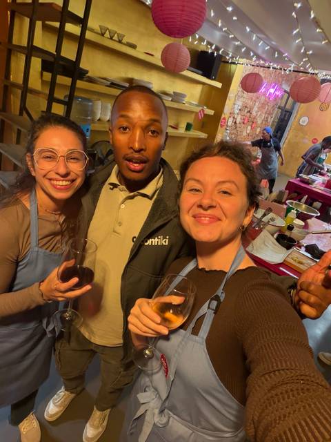 Three friends smiling indoors holding wine glasses during a social gathering.