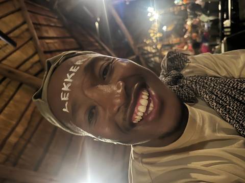 Close-up selfie of a smiling man with the word ‘LEKKER’ painted on his forehead.