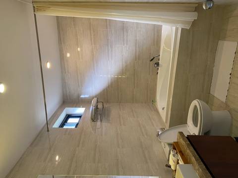 Clean hotel bathroom with bathtub, toilet and light tiled walls.