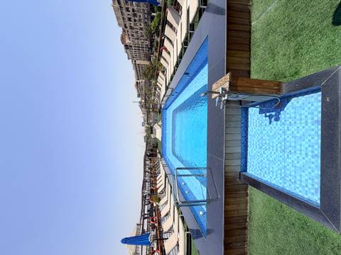 Rooftop swimming pool with bright blue water on a cruise ship deck under a clear sky.