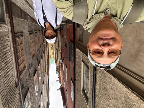 Selfie of couple standing in narrow cobblestone alley lined with colorful medieval facades of Stockholm’s Gamla Stan.