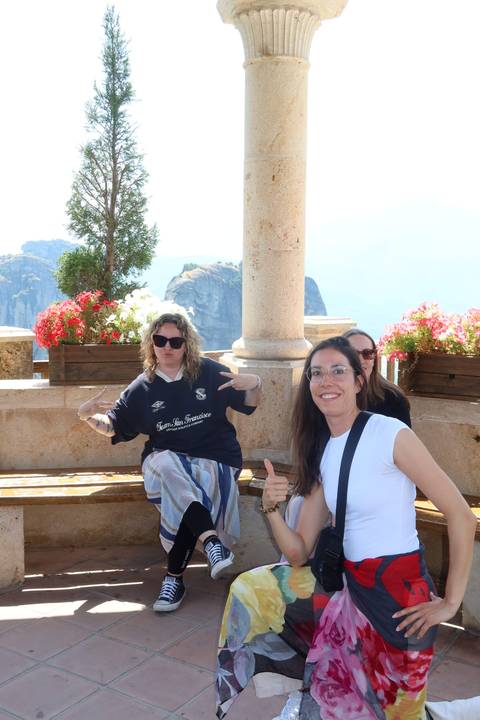 Travellers posing playfully with colourful flowers and towering rock pillars in the background.