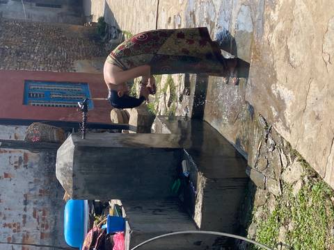 Woman rinsing her face at a communal outdoor tap in a rural village.
