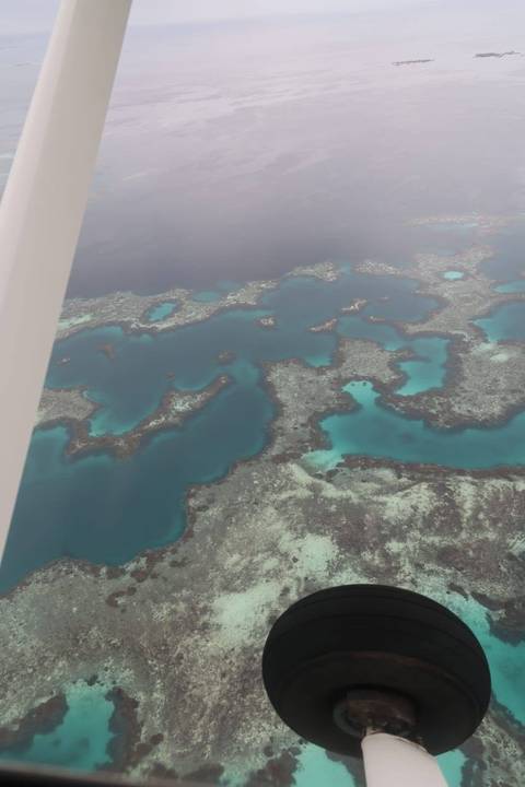 Aerial view of turquoise lagoons and intricate coral formations surrounded by deeper blue water.