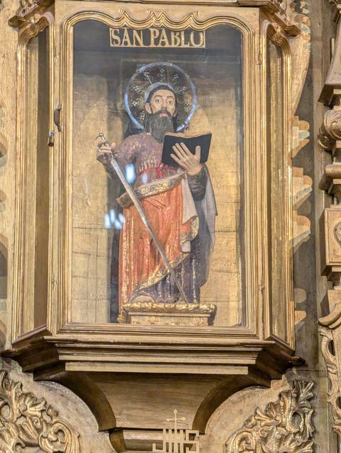 Detail of religious statue behind reflective glass inside a church.