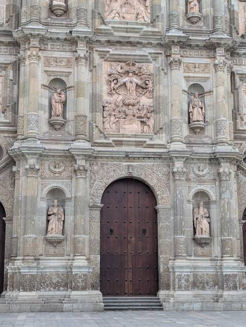 Elaborate stone baroque façade with richly carved columns and wooden doors.