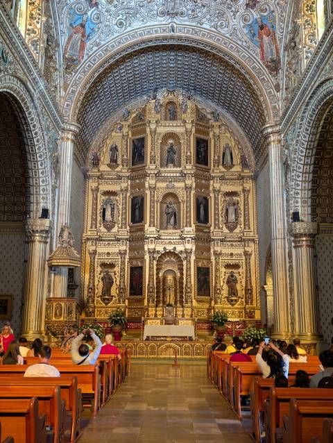 Opulent golden altarpiece and columns inside colonial church.
