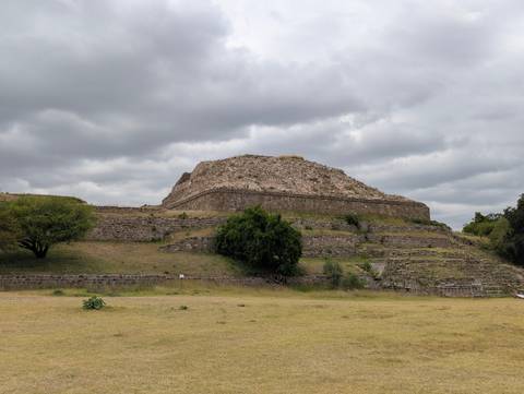 Ancient stone pyramid platform at Monte Albán under overcast skies.