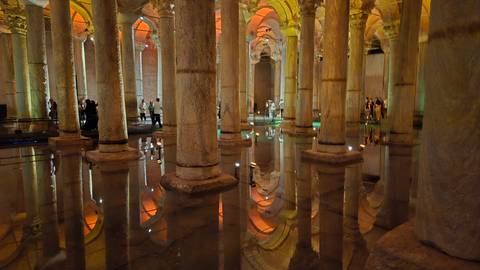 The atmospheric Basilica Cistern with stone columns reflecting in shallow water under warm orange lighting.