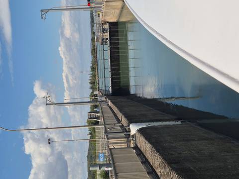 A lock gate and concrete walls guide a river vessel under a partly cloudy sky.