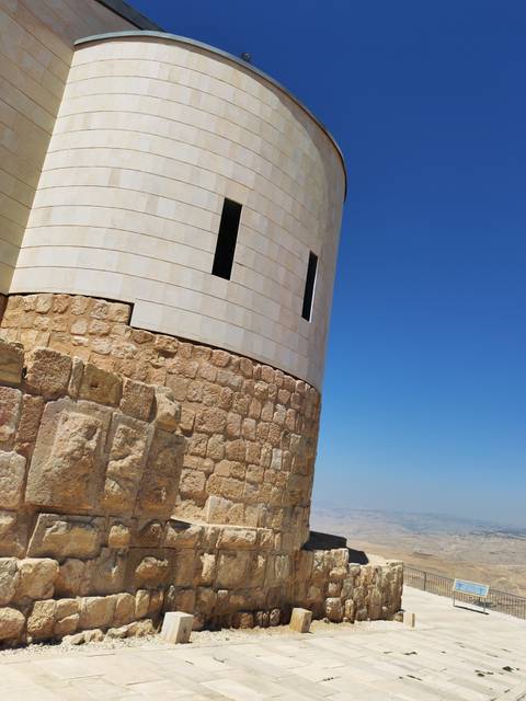 Close-up of a modern stone tower facade contrasting against clear blue sky.
