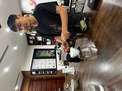 Barista prepares a manual pour-over coffee setup on a wooden countertop.