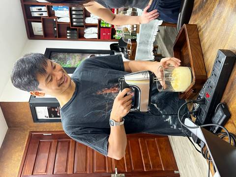 Smiling barista whips eggs with a handheld mixer during a coffee workshop.