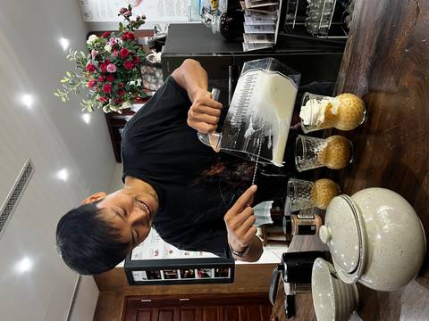 Barista pours creamy topping from a blender into individual glasses of Vietnamese coffee.