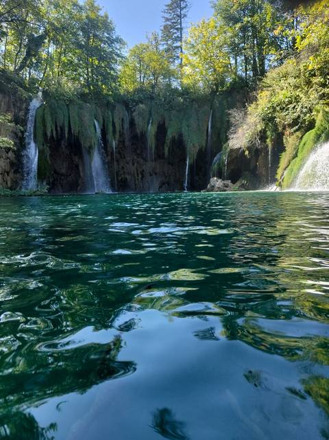 Clear turquoise pool with cascading waterfalls framed by moss-covered cliffs.