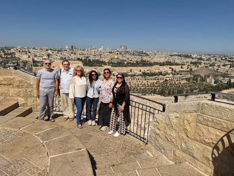 Small tour group poses on a lookout above Jerusalem with the Dome of the Rock and Old City in the background.