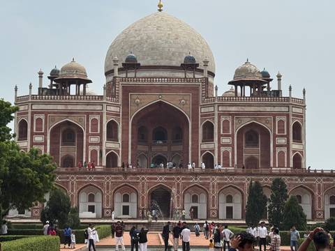 Imposing Humayun's Tomb in red sandstone and white marble with visitors on the upper terrace.