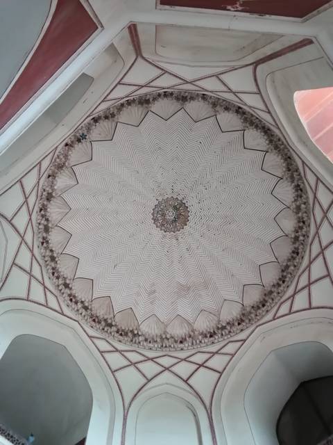 Intricate starburst marble ceiling pattern with geometric zig-zags inside a Mughal monument.