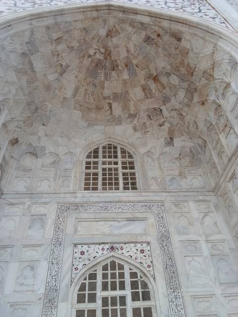 Pale marble wall with decorative arches and calligraphy panels inside the Taj Mahal complex.