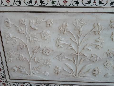 Detailed white marble relief carvings of flowers in the Taj Mahal.