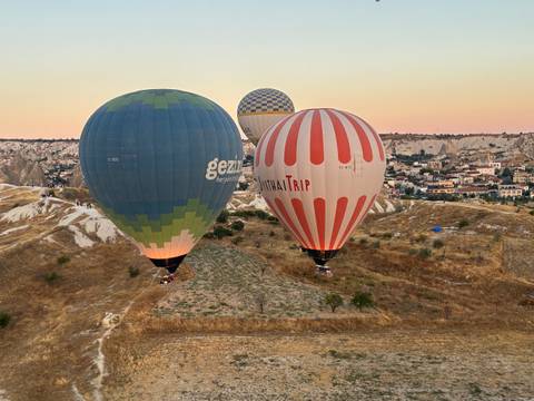 Colorful hot air balloons lift over Cappadocia’s arid hills at sunrise.