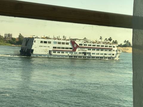 Cruise ship sails along the Nile viewed through a cabin window frame.