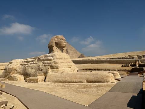 Side view of the Great Sphinx with Khafre’s pyramid rising behind under clear skies.