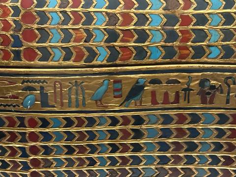 Detailed close-up of colourful inlaid hieroglyphic patterns on an ancient Egyptian coffin.