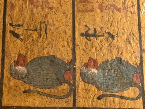 Detailed wall painting of sacred baboons with hieroglyphs on a golden background.