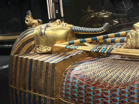 Close-up of Tutankhamun’s golden sarcophagus head and crossed arms with vibrant inlay detail.