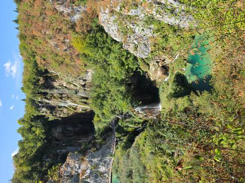 Panoramic view of emerald lakes and cascading waterfalls surrounded by lush forested cliffs.