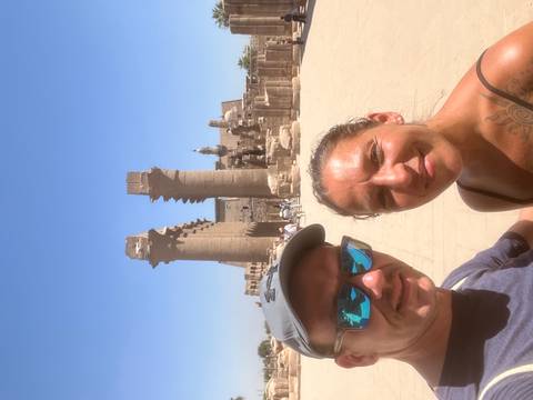 Selfie of couple at Luxor Temple with towering stone columns behind them.