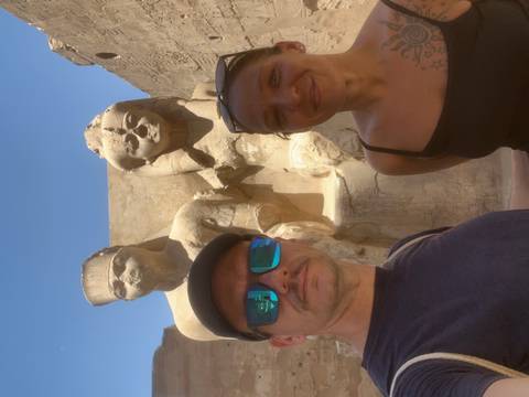 Couple poses beside two massive seated pharaoh statues carved from sandstone.