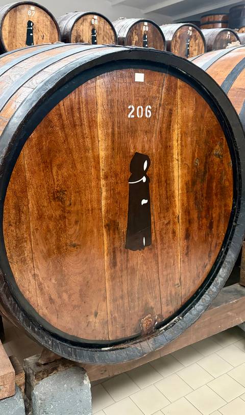 Wooden barrel head branded with silhouette of a cloaked figure.