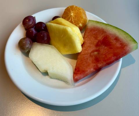 Plate of assorted fresh fruit slices including grapes, pineapple, melon and watermelon.