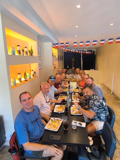 Group of travellers share a meal in a cozy restaurant decorated with small French flags.