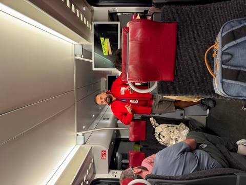 A guide in a red jacket addresses passengers inside a modern train carriage with a screen reading 'Jungfrau'.